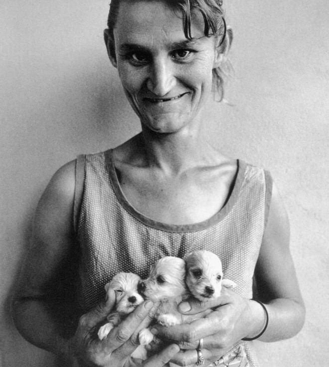 Wife of abattoir worker holding three puppies, Orange Free State